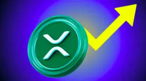 A financial candlestick chart on a dark digital screen showing a sharp, glowing green upward trend line ending in a bright arrow. Above the peak of the arrow, a glowing blue XRP cryptocurrency logo is displayed against the dark, blurred background of the trading interface.